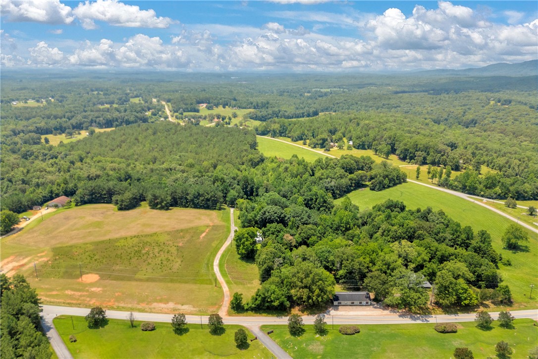 100 Newberry Road Walhalla, SC 29691 - Photo 6 of 13 Vast green acreage unfolds with distant hills, featuring a single dwelling amidst lush woodland.