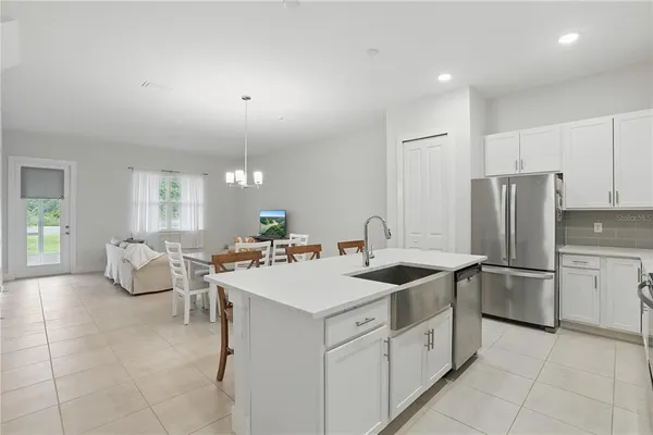 a kitchen that has a lot of white cabinets and stainless steel appliances