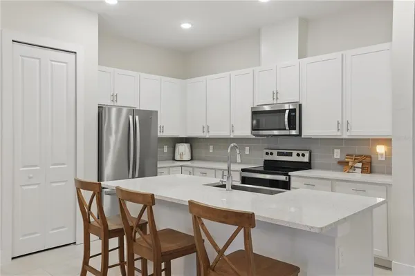 a kitchen with stainless steel appliances a refrigerator a stove a sink dishwasher and white cabinets with wooden floor