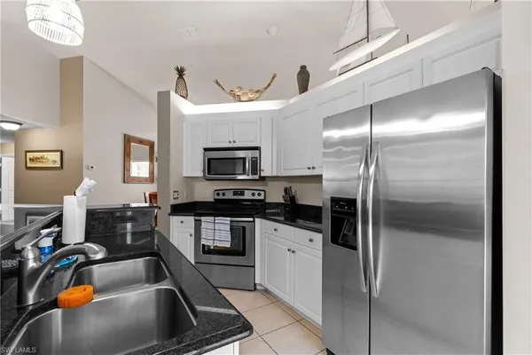 a kitchen with stainless steel appliances granite countertop a refrigerator a stove and a sink with wooden floor