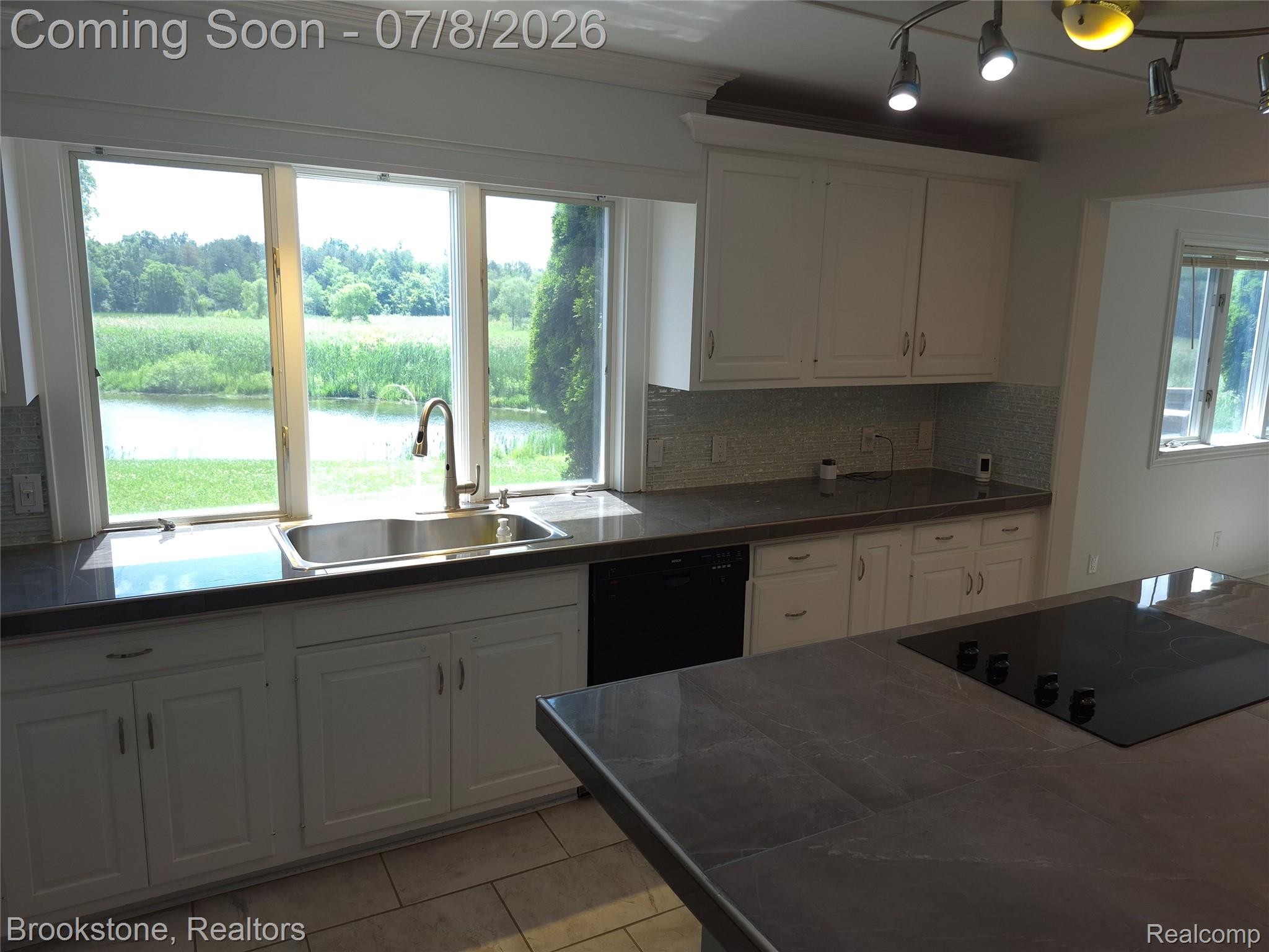 4140 South Henderson Road Davison, MI 48423 - Photo 26 of 98 Kitchen featuring white cabinetry, gray countertops, a stainless steel sink with a gooseneck faucet, a tile backsplash, and an integrated cooktop on the island