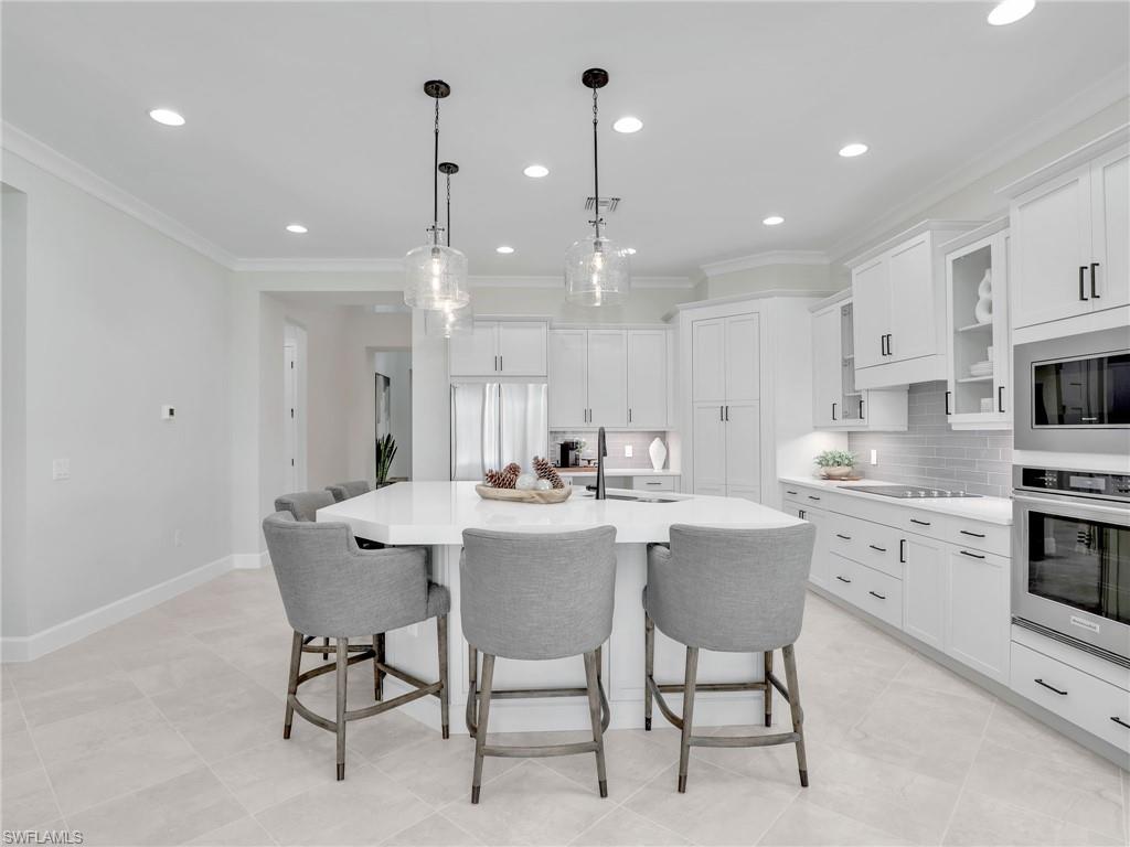 8850 Calypso Court Naples, FL 34113 - Photo 11 of 49 a kitchen with appliances a sink cabinets and a counter top space