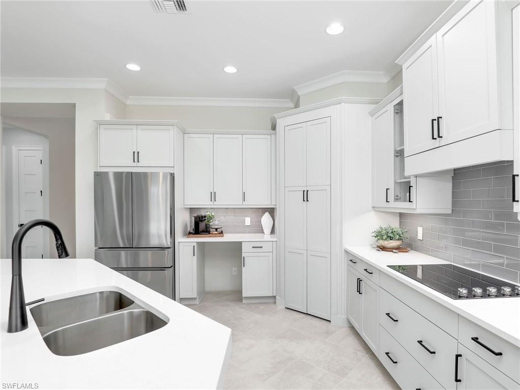 8850 Calypso Court Naples, FL 34113 - Photo 13 of 49 a kitchen that has a sink a refrigerator and cabinets