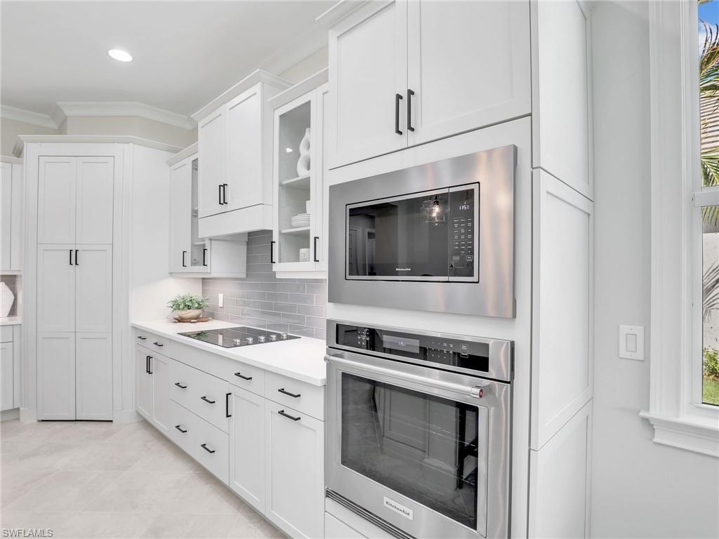 8850 Calypso Court Naples, FL 34113 - Photo 14 of 49 a kitchen with stainless steel appliances white cabinets and a fireplace