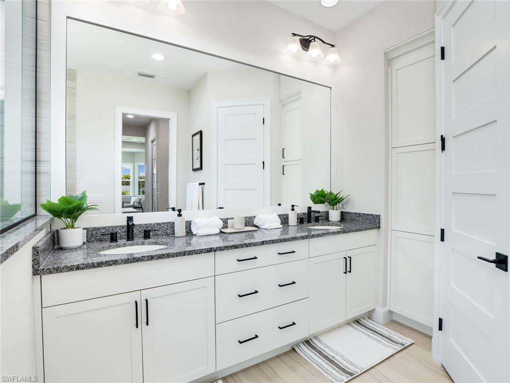 8850 Calypso Court Naples, FL 34113 - Photo 21 of 49 a bathroom with a granite countertop sink a mirror and a shower