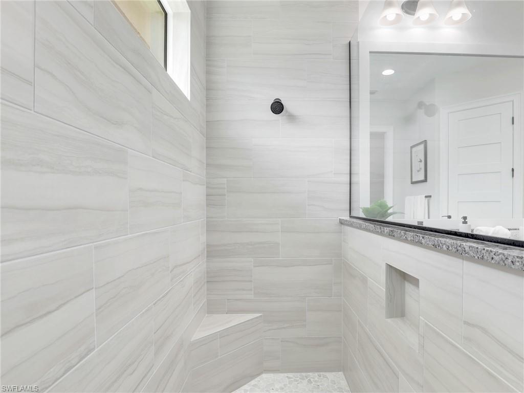 8850 Calypso Court Naples, FL 34113 - Photo 25 of 49 a bathroom with a granite countertop sink a mirror and shower