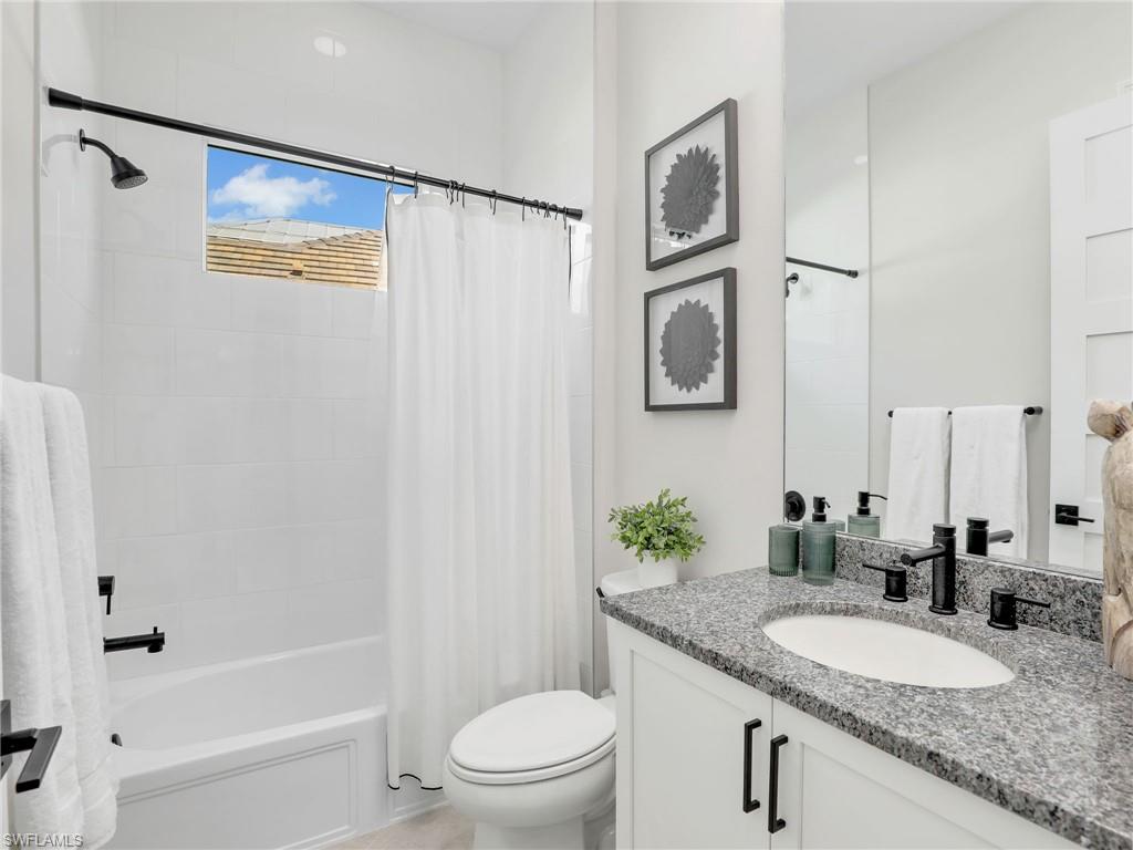 8850 Calypso Court Naples, FL 34113 - Photo 26 of 49 a bathroom with a granite countertop sink toilet and a mirror
