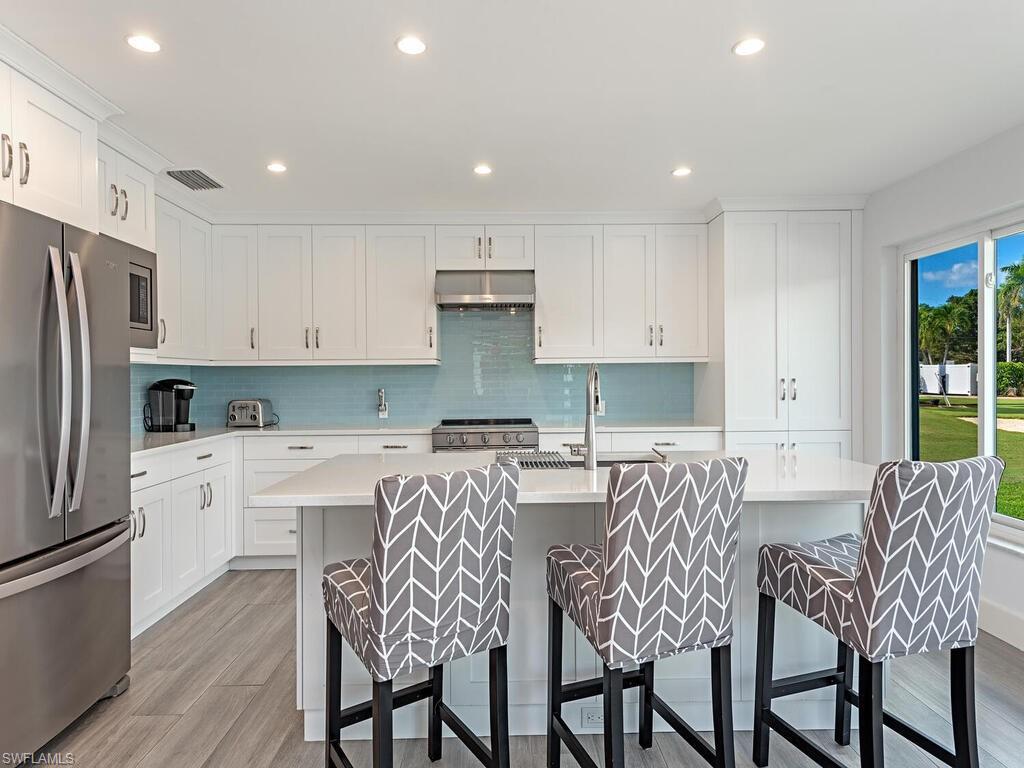 595 Wedge Drive Naples, FL 34103 - Photo 11 of 17 a kitchen with stainless steel appliances granite countertop a table and chairs