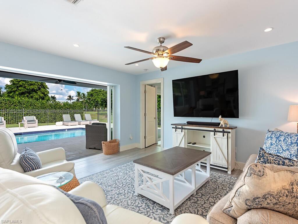 595 Wedge Drive Naples, FL 34103 - Photo 6 of 17 a living room with furniture a flat screen tv and a floor to ceiling window