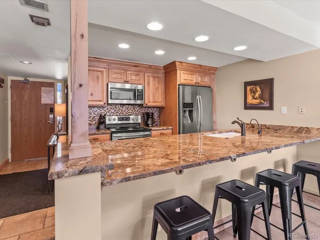 a kitchen with stainless steel appliances granite countertop a stove top oven a sink a dining table and chairs