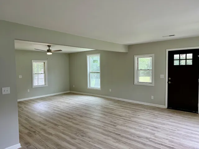 a view of an empty room with wooden floor and a window