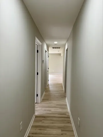 a view of a hallway with wooden floor and staircase