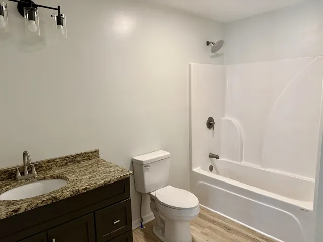 a bathroom with a granite countertop sink toilet and shower