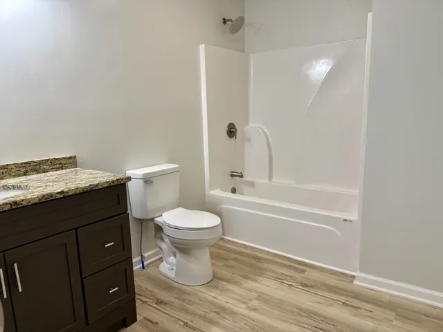 a bathroom with a granite countertop toilet a sink and bathtub