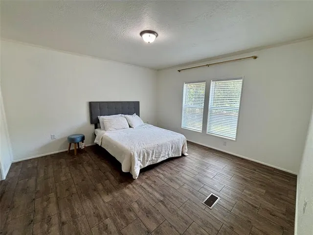 a bed sitting in a spacious bedroom next to a window and a larger closet