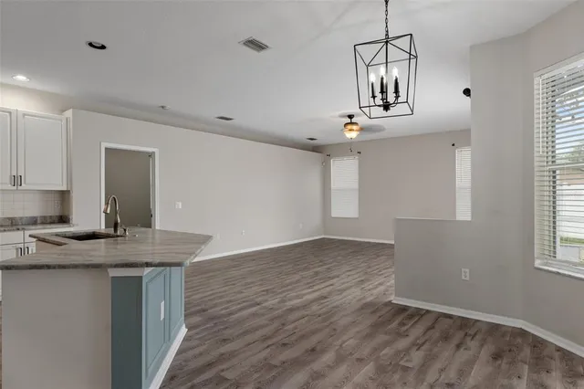 a view of an empty room with wooden floor and a ceiling fan