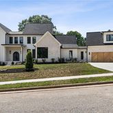 a view of a white house next to a yard with big trees