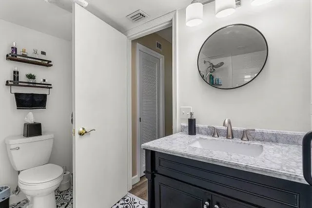 a bathroom with a granite countertop toilet sink and mirror