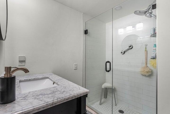 10110 Cedar Point Boulevard, Unit 203 Boynton Beach, FL 33437 - Photo 13 of 37 a bathroom with a granite countertop sink a toilet and shower