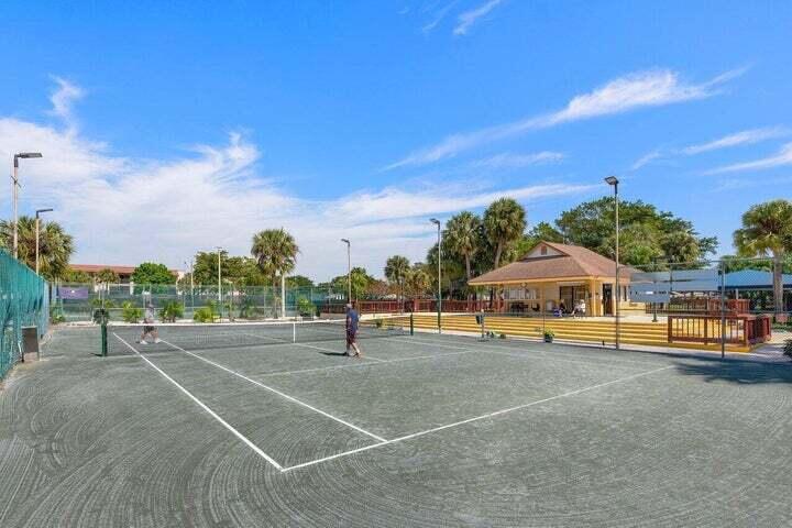 10110 Cedar Point Boulevard, Unit 203 Boynton Beach, FL 33437 - Photo 28 of 37 a view of a tennis ground with a large trees