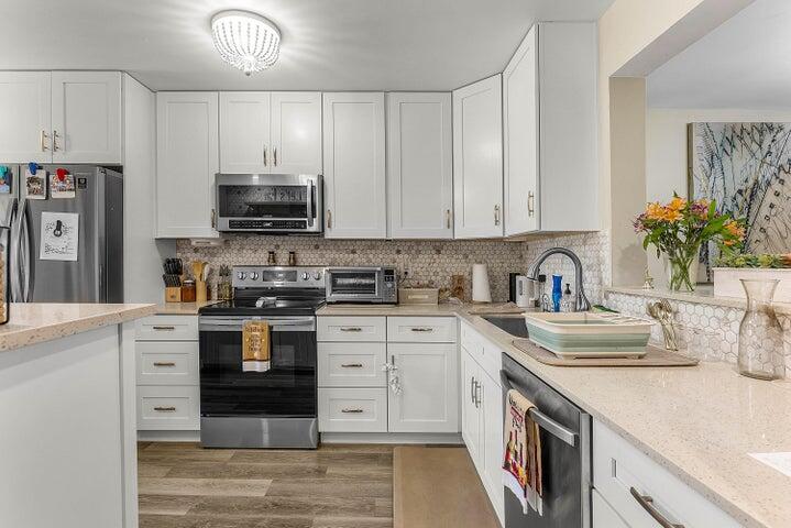 10110 Cedar Point Boulevard, Unit 203 Boynton Beach, FL 33437 - Photo 10 of 37 a kitchen with kitchen island granite countertop a sink stainless steel appliances and white cabinets