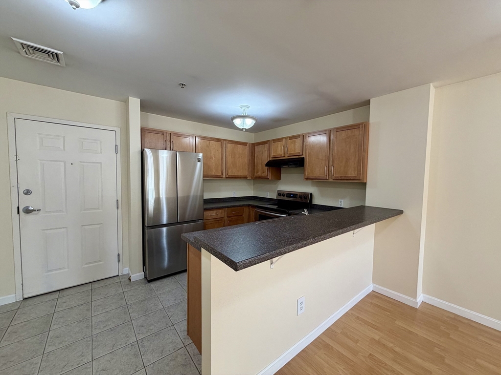 75 Walnut Street, Unit 312 Peabody, MA 01960 - Photo 4 of 16 a kitchen with granite countertop a sink and a refrigerator