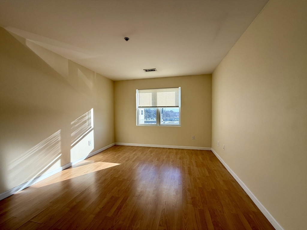 75 Walnut Street, Unit 312 Peabody, MA 01960 - Photo 6 of 16 an empty room with wooden floor cabinet and windows