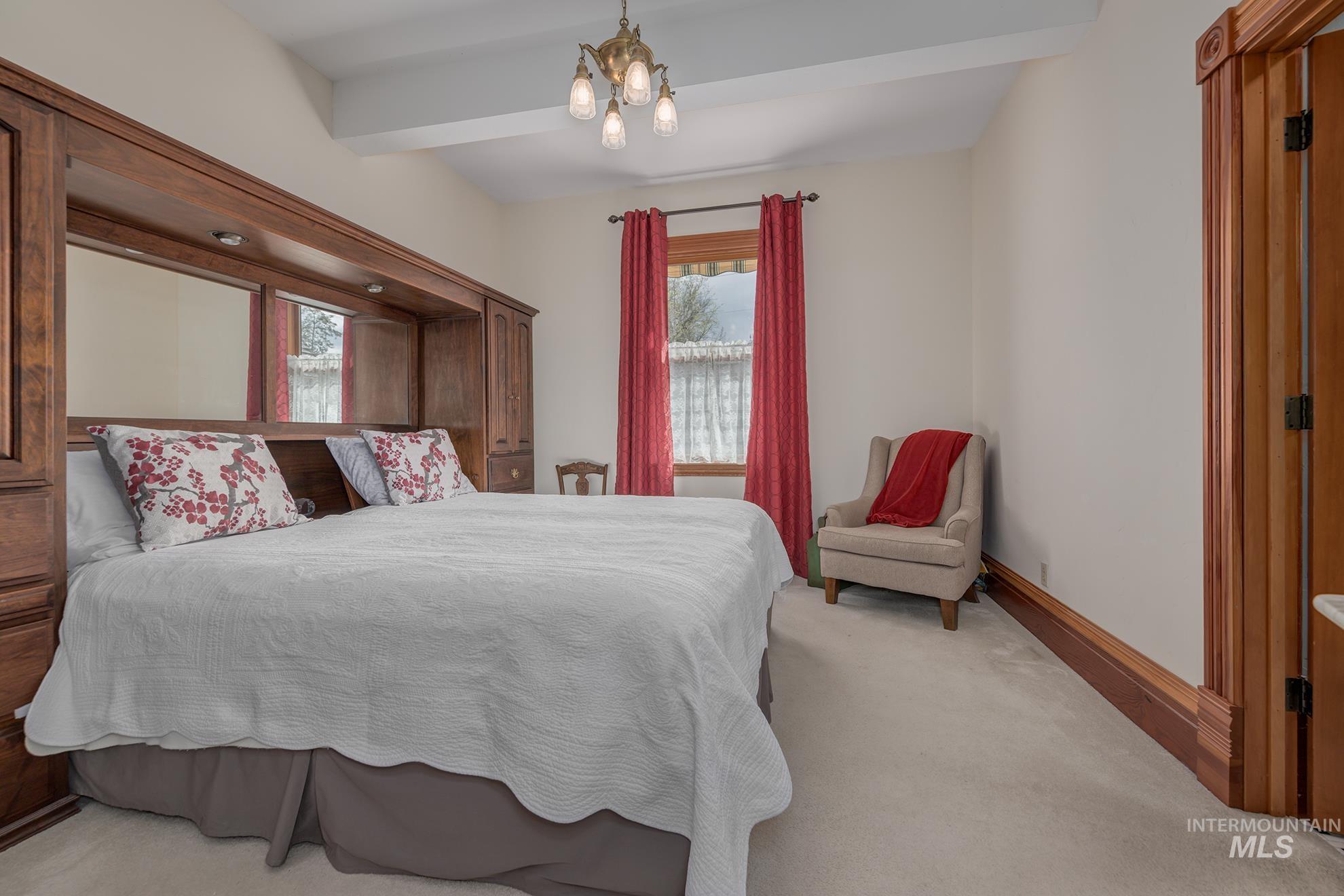 548 West 2nd Street Weiser, ID 83672 - Photo 17 of 50 Bedroom with a chandelier, light carpet, and beamed ceiling