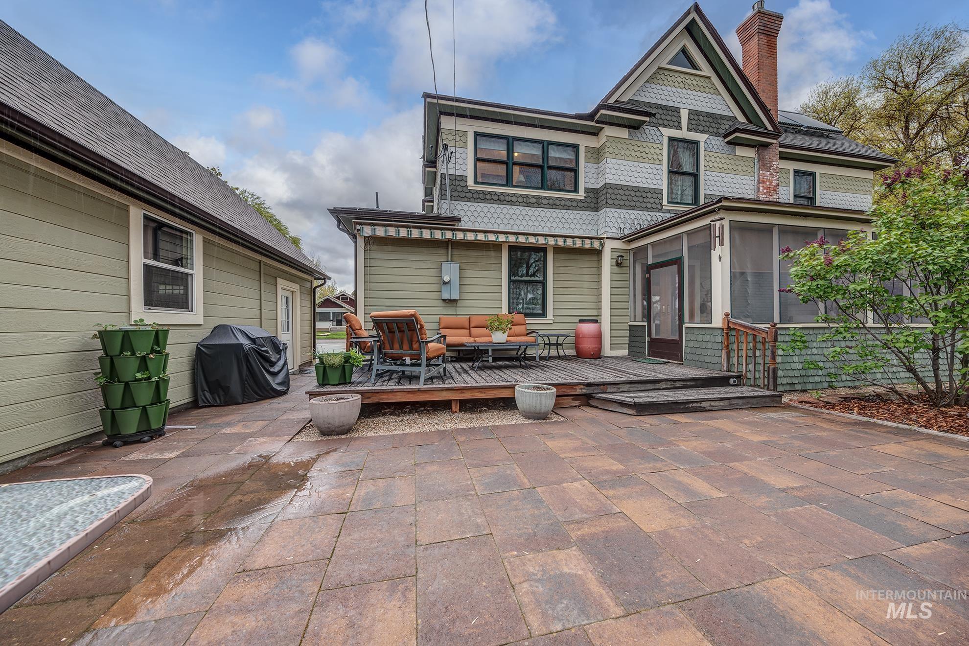 548 West 2nd Street Weiser, ID 83672 - Photo 39 of 50 Back of house featuring a wooden deck, a sunroom, an outdoor living space, and a chimney