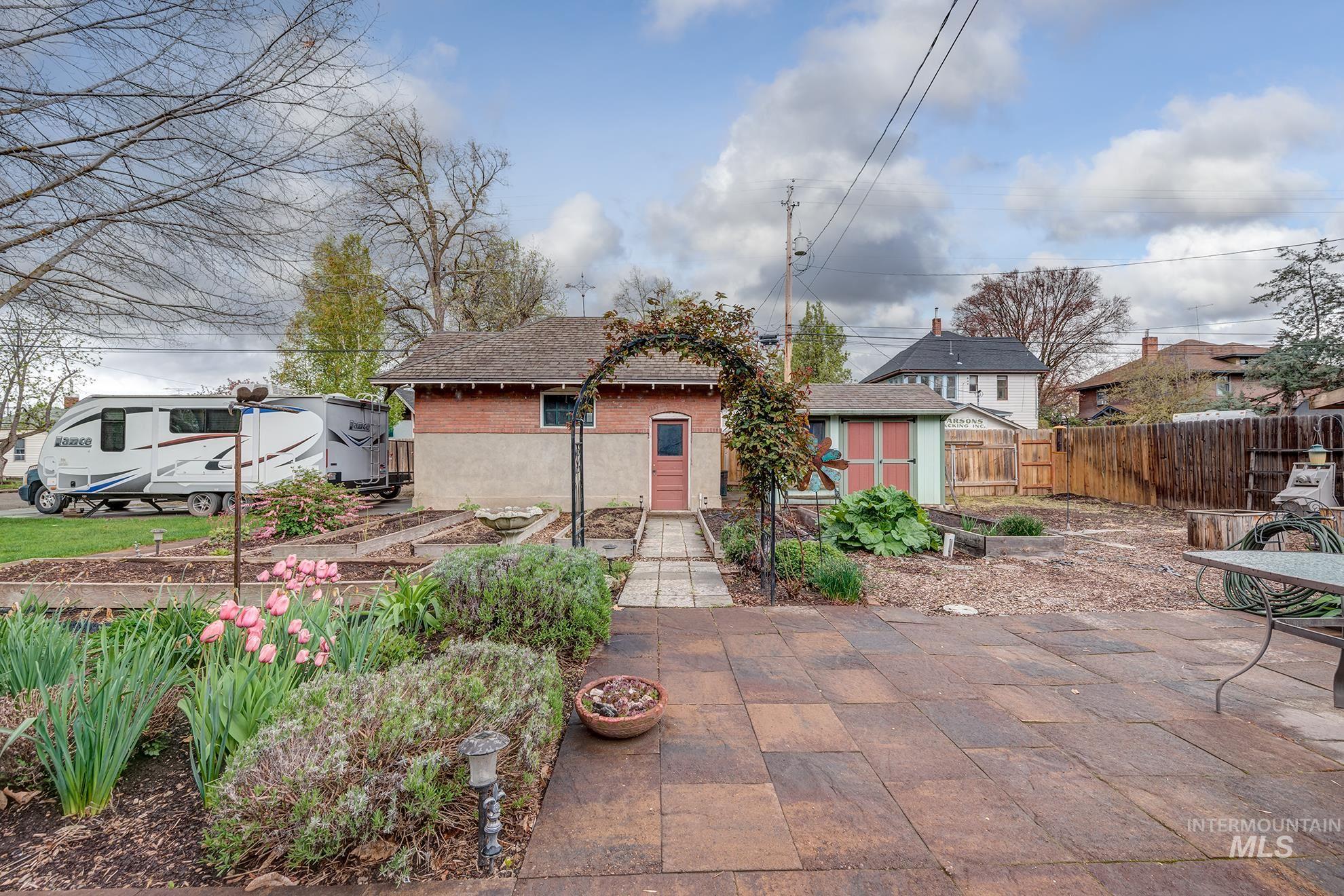 548 West 2nd Street Weiser, ID 83672 - Photo 42 of 50 View of front of house with a vegetable garden, a shed, a shingled roof, brick siding, and a patio area