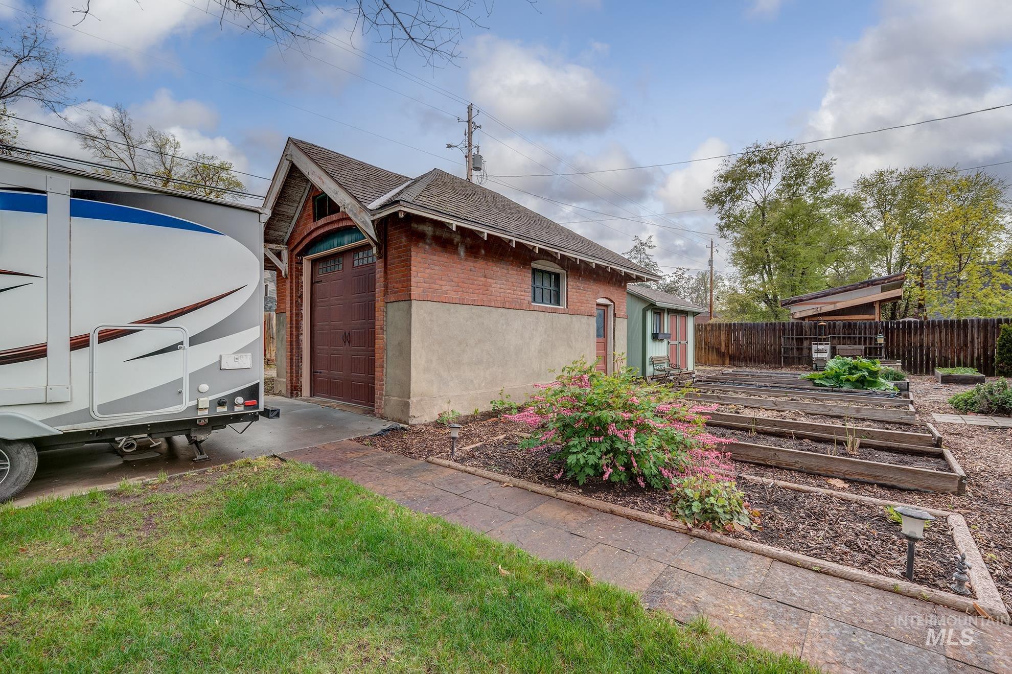 548 West 2nd Street Weiser, ID 83672 - Photo 43 of 50 View of home's exterior featuring brick siding, roof with shingles, a vegetable garden, and an outdoor structure