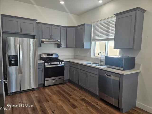 a kitchen with granite countertop a refrigerator stove and sink