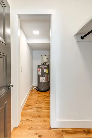 a view of a hallway with wooden floor and a bathroom