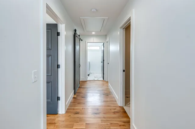 a view of an empty room with a window and wooden floor