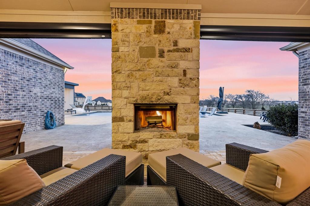7751 Faught Road Northlake, TX 76226 - Photo 32 of 39 Outdoor living space featuring a stone fireplace, integrated ceiling lighting, and a paved patio extending to a swimming pool