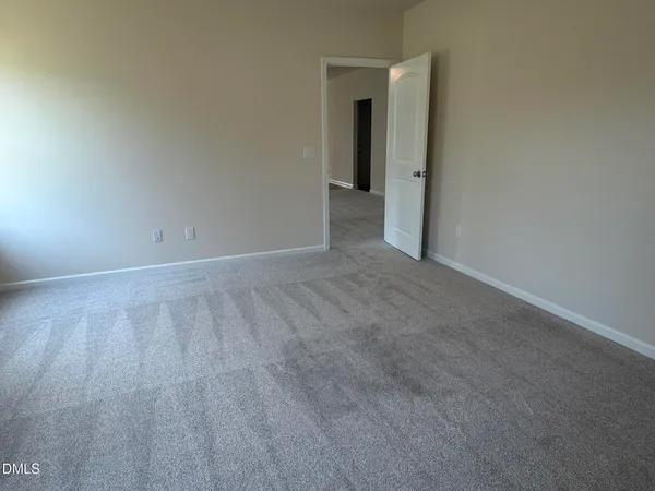 a view of an empty room with closet and a window