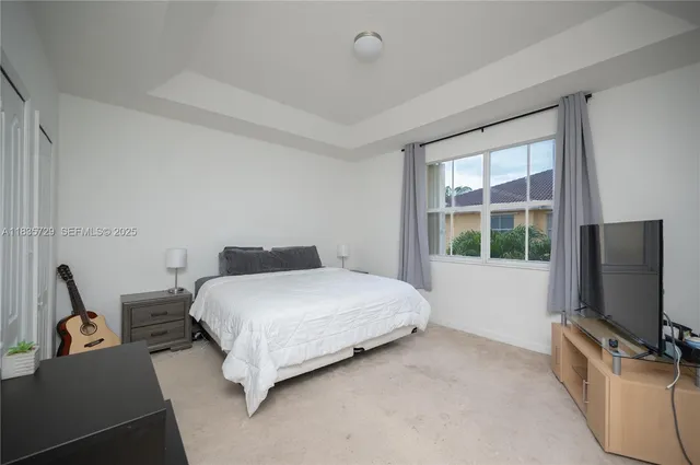 a bedroom with a bed flat screen tv and a window