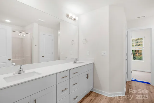 a bathroom with a double vanity sink and mirror with shower