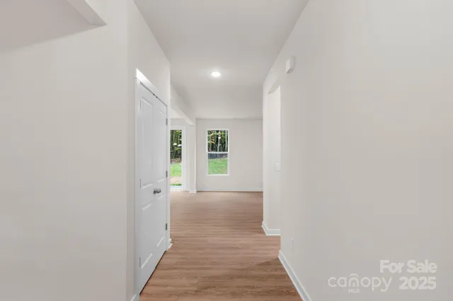 a view of a hallway with wooden floor and a window