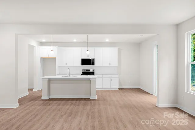 a view of kitchen with microwave stove refrigerator and cabinets
