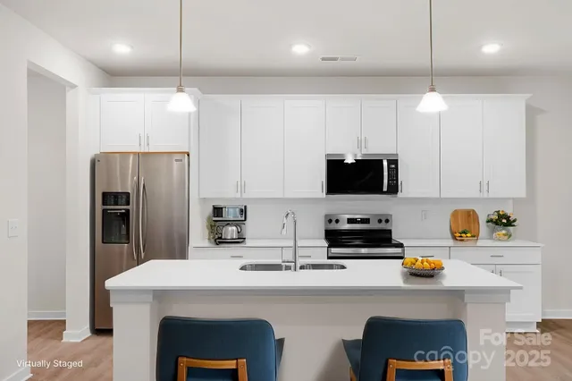 a kitchen with stainless steel appliances a stove refrigerator a sink a stove a dining table and chairs