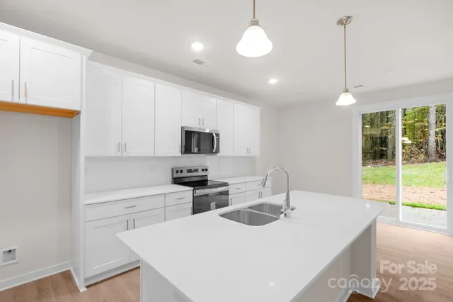 a kitchen with stainless steel appliances a sink a stove a refrigerator cabinets and a window