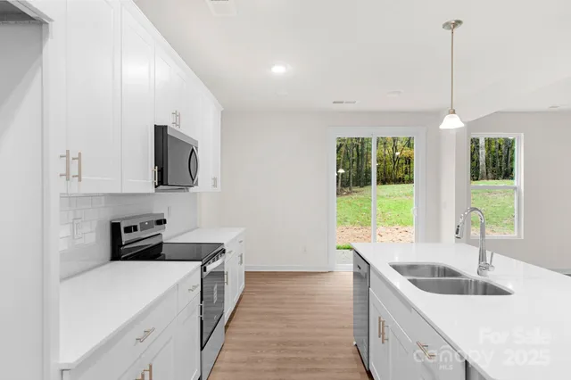 a kitchen that has a sink a stove and a wooden floor