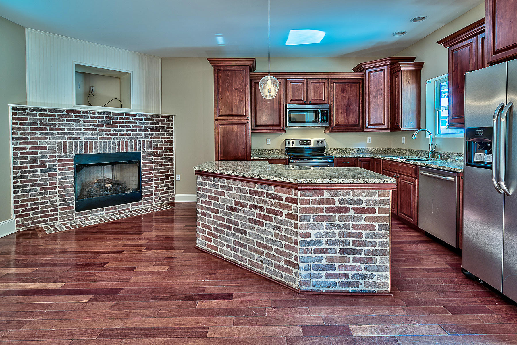 239 Inverrary Drive Destin, FL 32541 - Photo 3 of 20 a kitchen with granite countertop a stove top oven a sink dishwasher and a fireplace with wooden floor