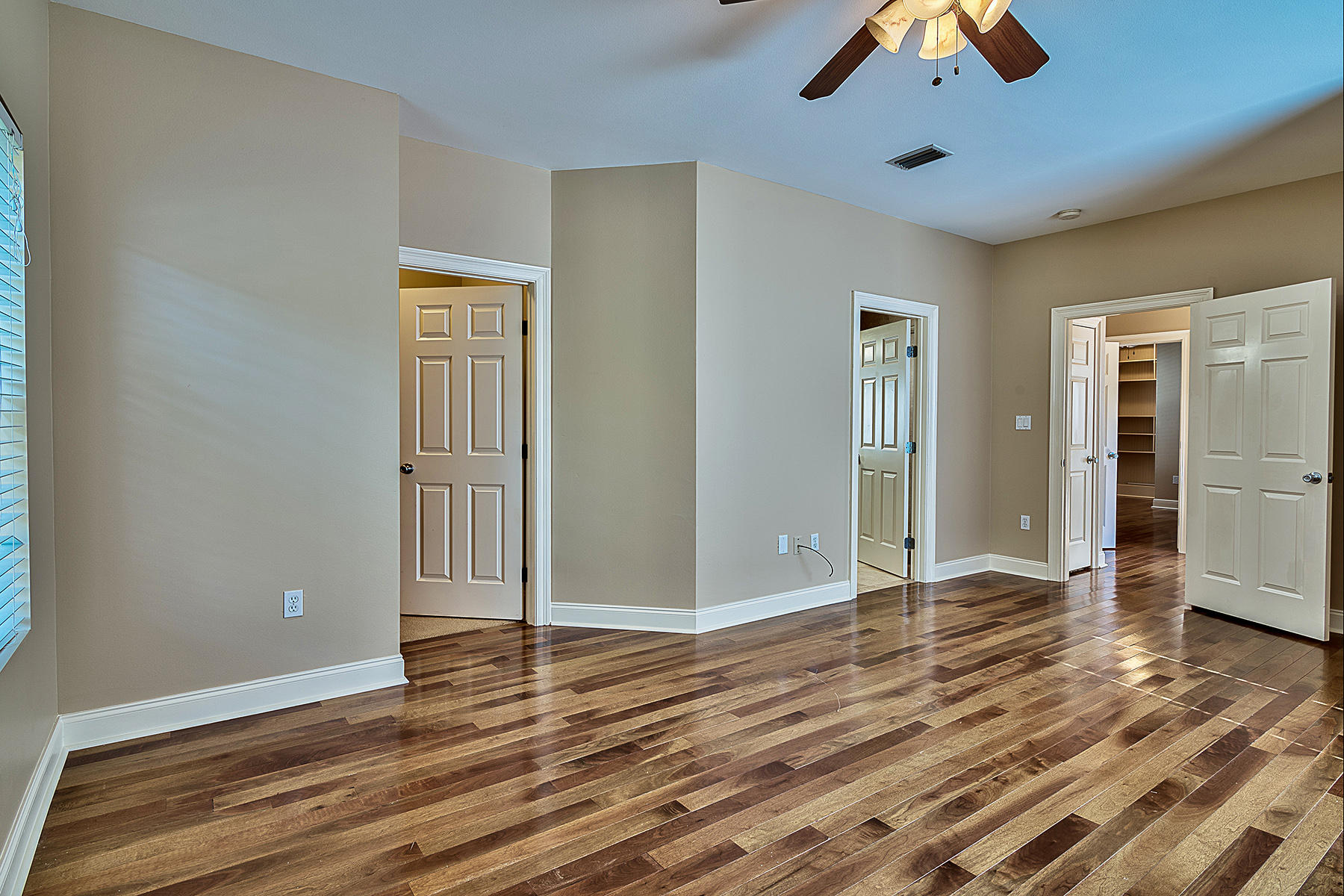 239 Inverrary Drive Destin, FL 32541 - Photo 5 of 20 an empty room with wooden floor chandelier fan and windows