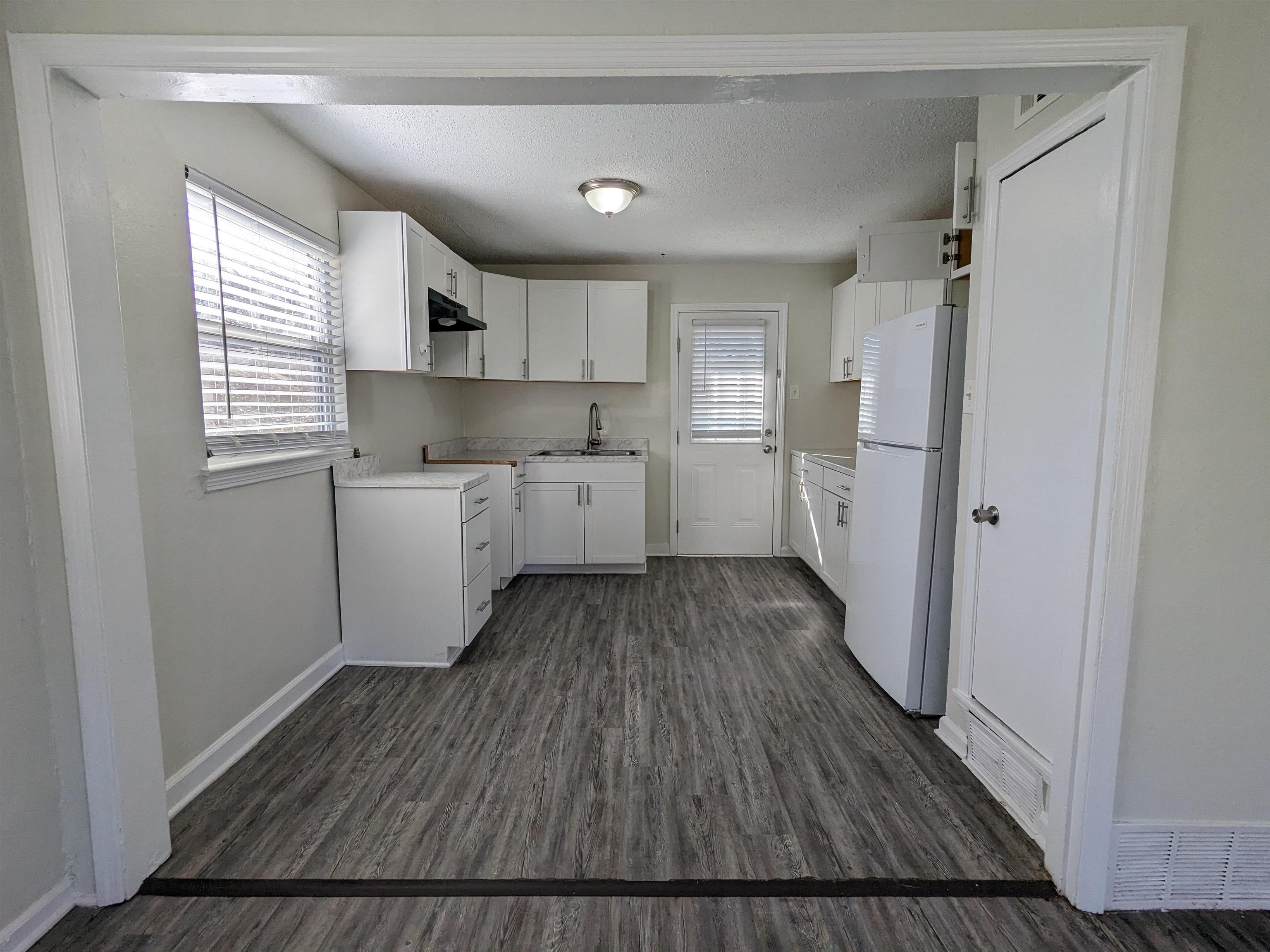 4499 Range Line Road Memphis, TN 38127 - Photo 2 of 10 a kitchen with wooden floors and white cabinets