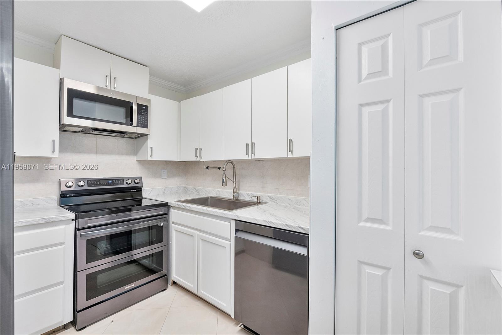 8050 Northwest 8th Street, Unit 1203 Miami, FL 33126 - Photo 4 of 14 a kitchen with white cabinets and stainless steel appliances