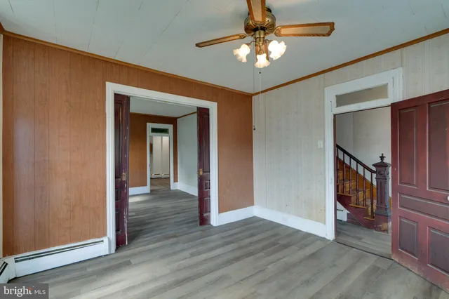 an empty room with wooden floor chandelier fan and windows