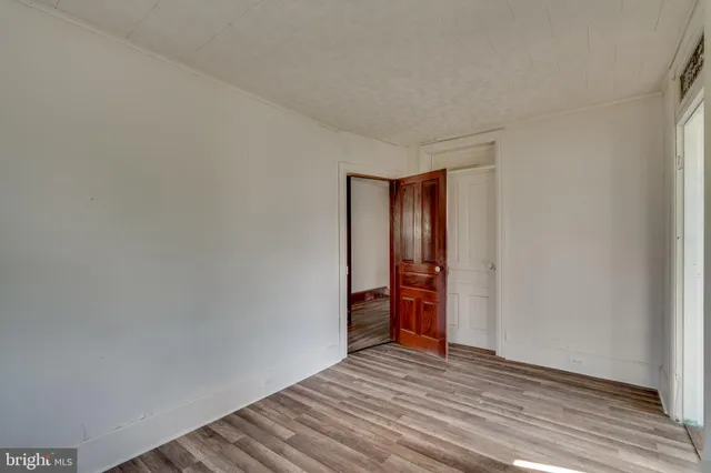 a view of an empty room with wooden floor and closet