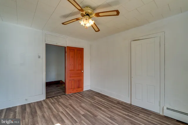 wooden floor in an empty room with a chandelier fan
